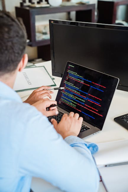 Close-up image of a computer screen displaying lines of programming code in various colors, including pink, yellow, green, blue, and white, on a dark background. The code features typical syntax eleme